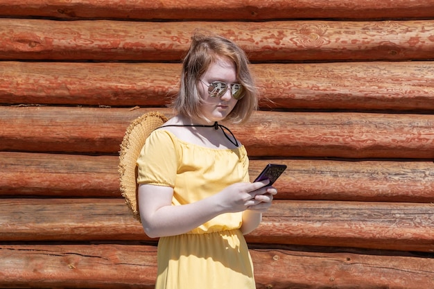 Adolescente asiatique en robe jaune chapeau et lunettes de soleil fait des achats en ligne sur le téléphone communique