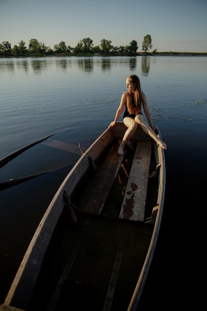 Photo une adolescente assise sur un bateau dans un lac contre le ciel