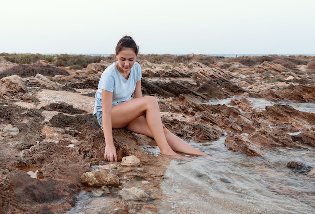 Adolescente assise sur la falaise au bord de la mer