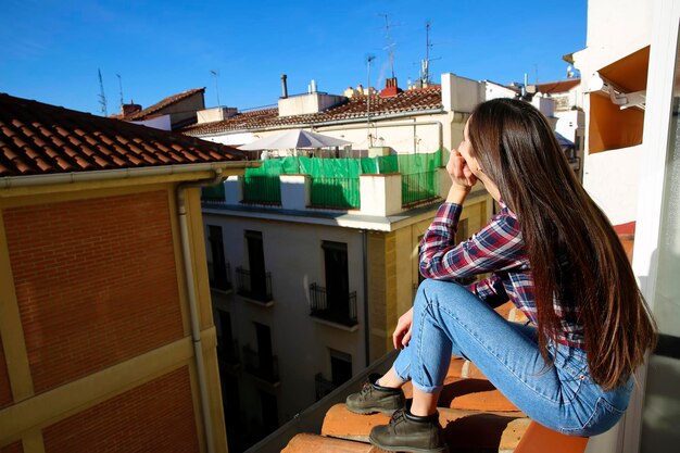 Adolescente assise sur le toit de la vieille ville