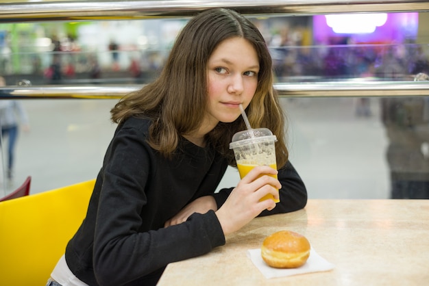 Adolescente au café manger du gâteau et du jus d'orange