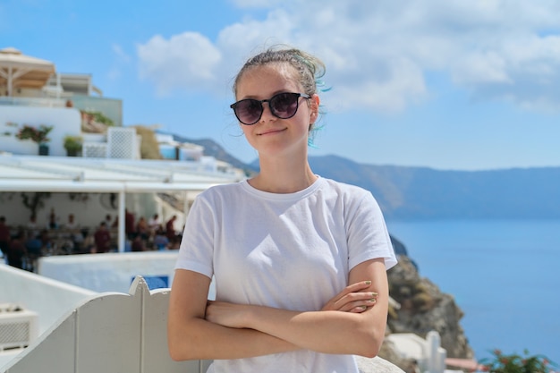 Adolescente au repos sur l'île grecque de Santorin, femme regardant la caméra, l'architecture blanche de fond du village d'Oia, mer, ciel dans les nuages