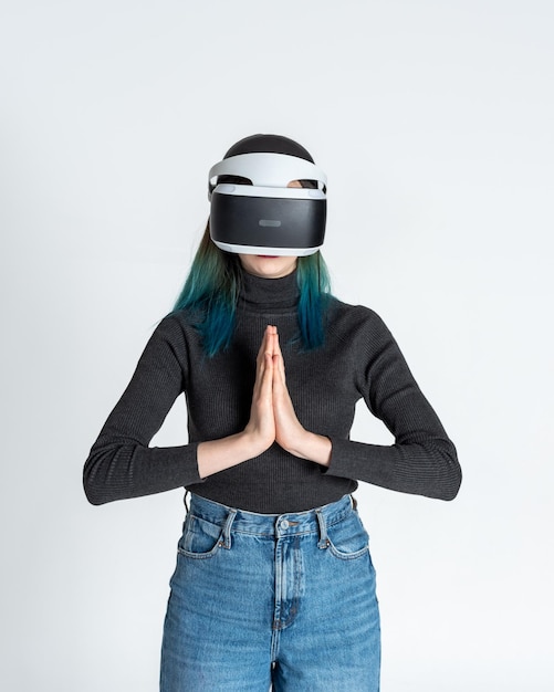 Une adolescente aux cheveux bleus portant des lunettes de réalité virtuelle regarde des films ou joue à des jeux vidéo montre un signe de gratitude