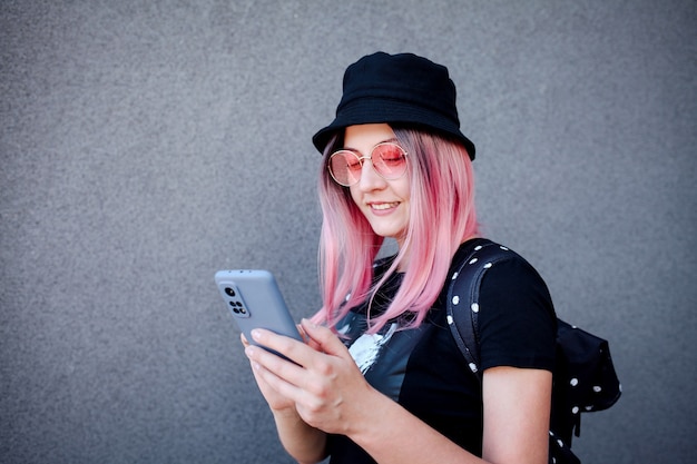 Une adolescente aux cheveux roses à l'aide d'un smartphone un jour d'été dans la rue