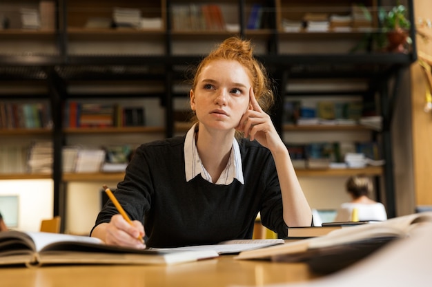 Adolescente aux cheveux rouges concentré étudiant