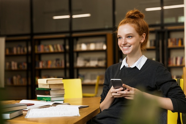 Adolescente aux cheveux rouges positive étudie à la table