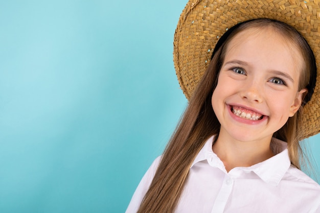 Une adolescente aux yeux gris, beau sourire et avec un chapeau souriant isolé sur bleu