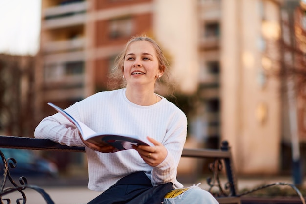 Une adolescente blonde absorbée par un livre sur le banc du parc.