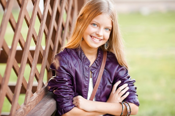 Photo adolescente blonde souriante posant à l'extérieur sur fond de nature verdoyante