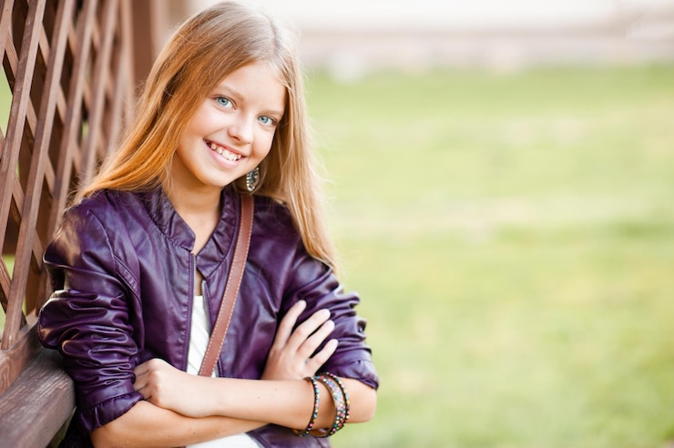 Photo adolescente blonde souriante posant à l'extérieur sur fond de nature verdoyante