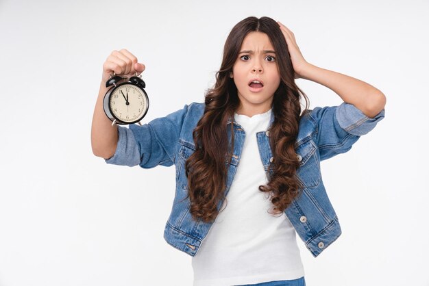 Photo une adolescente caucasienne choquée tenant une horloge isolée sur un fond blanc