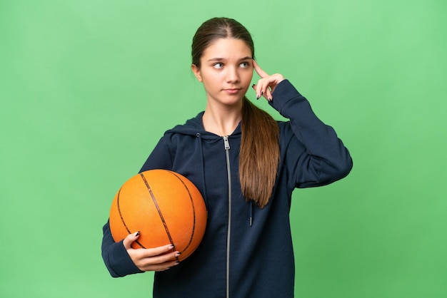 Adolescente caucasienne jouant au basket-ball sur fond isolé ayant des doutes et pensant