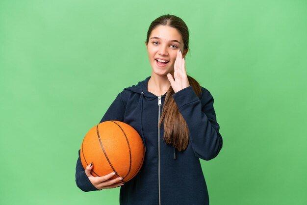 Adolescente caucasienne jouant au basket-ball sur fond isolé criant avec la bouche grande ouverte