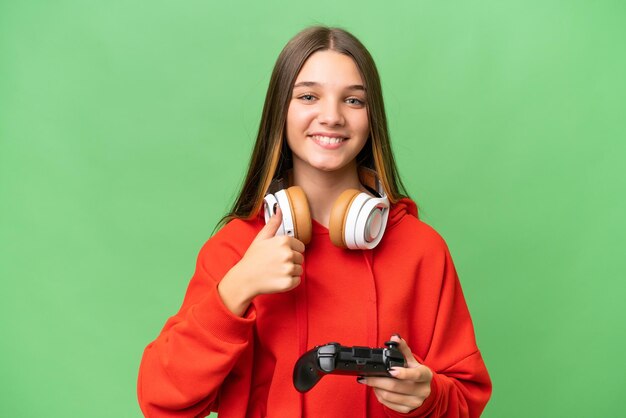 Adolescente caucasienne jouant avec un contrôleur de jeu vidéo sur fond isolé donnant un geste du pouce levé