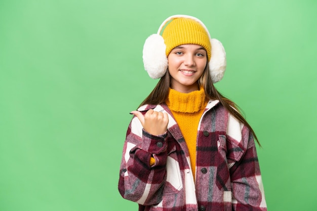 Adolescente caucasienne portant des manchons d'hiver sur fond isolé pointant vers le côté pour présenter un produit