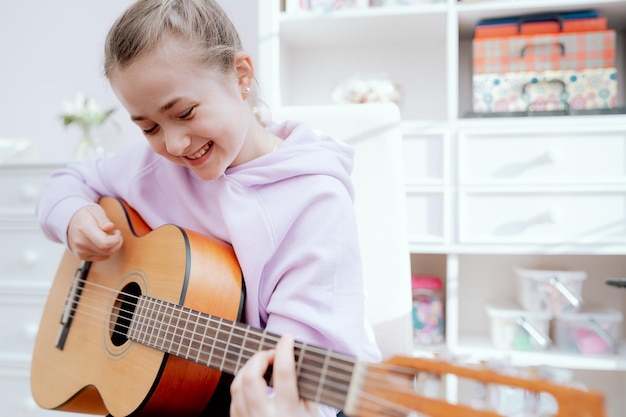 Une adolescente caucasienne souriante profite de son temps libre pour jouer de la guitare acoustique