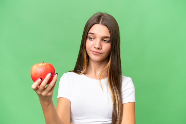 Adolescente caucasienne tenant une pomme sur fond isolé avec une expression triste