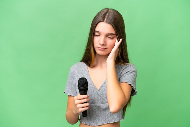 Photo adolescente chanteuse prenant un microphone sur fond isolé avec maux de tête