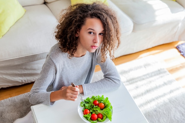 Adolescente, cheveux bouclés, manger salade