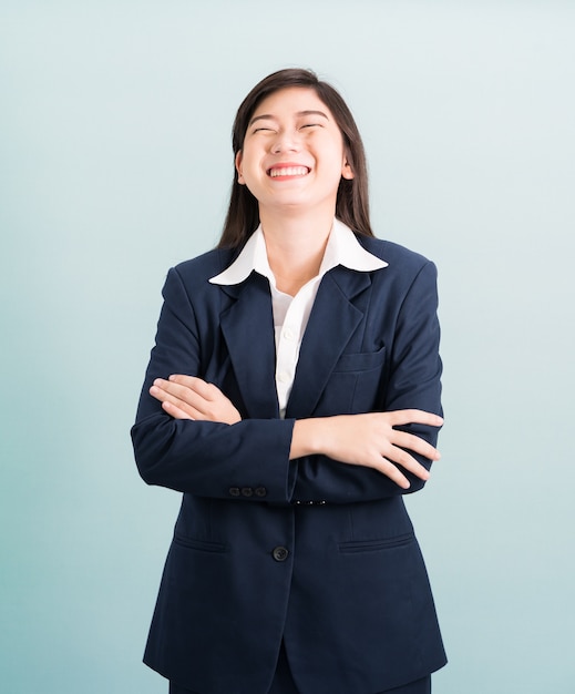 Adolescente cheveux longs est debout avec ses bras croisés portant costume et chemise blanche sur fond bleu