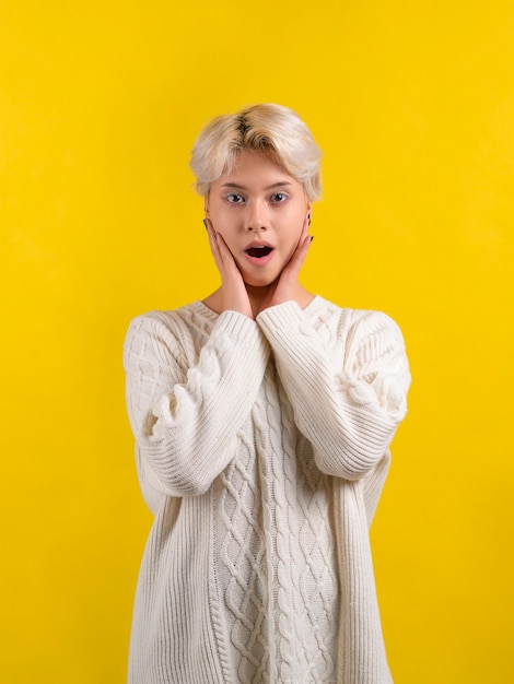 Adolescente choquée avec une courte coupe de cheveux blanche portant un pull en tricot blanc