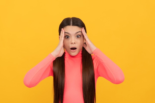 Adolescente choquée avec de longs cheveux sur les émotions de fond jaune