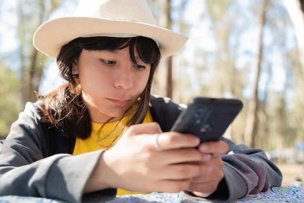 Adolescente con sombrero usando telefono smarphone