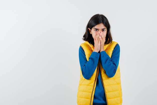 L'adolescente couvre sa bouche avec les mains sur fond blanc