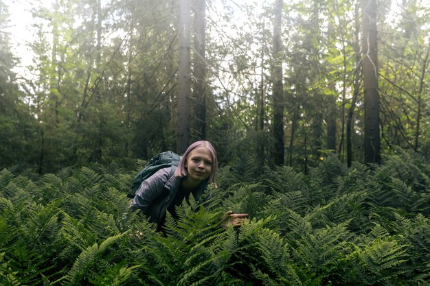 Une adolescente dans une forêt brumeuse parmi les fougères est passionnée par la nature