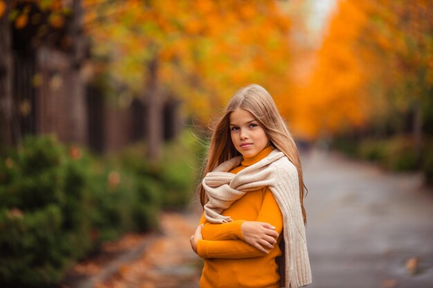 Photo une adolescente dans un pull jaune se promène le long d'une rue en dehors de la ville sur la toile de fond des arbres jaunes promenade amusante en automne