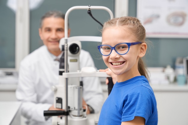 Adolescente dans des verres bleus posant avec un médecin en clinique.