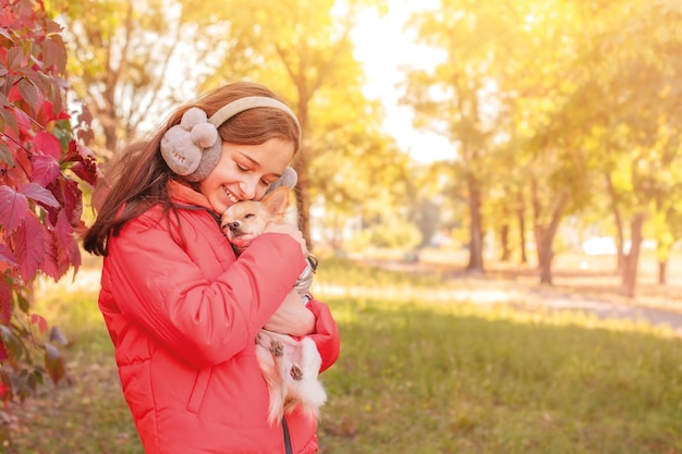 Une adolescente dans une veste orange avec un chien chihuahua dans ses bras La jeune fille étreint son chien