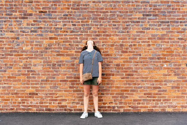 Photo une adolescente debout contre un mur de briques.