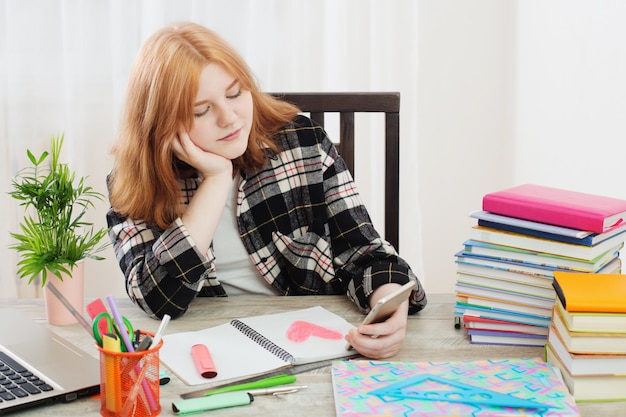 Adolescente a dessiné un cœur dans un cahier et regarde l'écran du smartphone, concept de premier amour