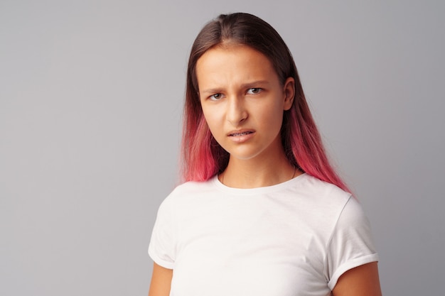 Adolescente drôle confuse regardant la caméra sur fond gris