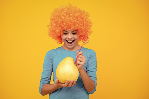 Photo adolescente drôle tenir agrumes pomelo ou pomelo gros pamplemousse vert isolé sur fond jaune portrait d'adolescent heureux fille souriante