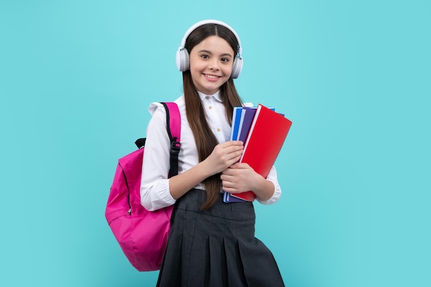 Adolescente de l'école 12 13 14 ans dans des écouteurs et des livres sur fond de studio isolé