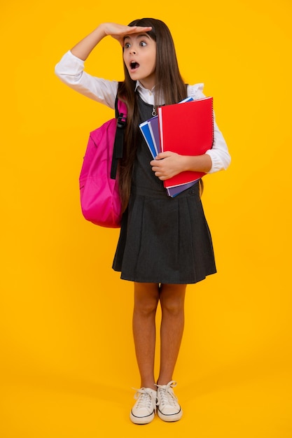 Adolescente de l'école avec sac à dos cartable tenir livre sur fond de studio isolé jaune