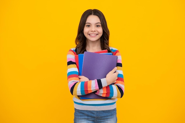 Adolescente élève tenir des cahiers de livres isolés sur fond jaune espace de copie Retour à l'école mode de vie chez les adolescentes éducation et connaissances