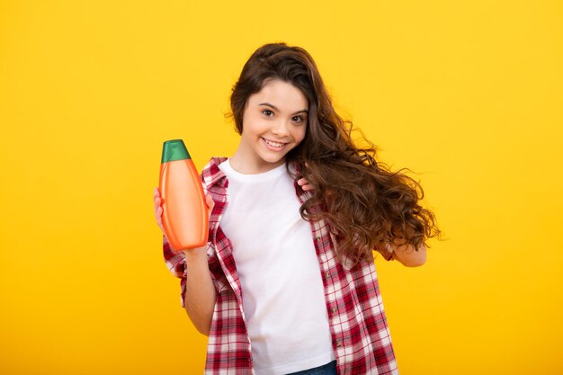 Adolescente enfant fille avec bouteille de shampoing revitalisants ou gel douche Soins capillaires pour enfants Bouteille de shampoing de produit cosmétique pour cheveux Heureux adolescent émotions positives et souriantes d'une adolescente