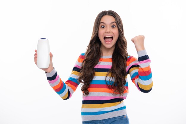 Adolescente enfant fille montrant des conditionneurs de shampooing en bouteille ou un gel douche isolé sur blanc
