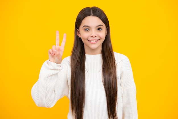 Adolescente enfant fille montrant les doigts signe de victoire numéro deux symbole vsign isolé sur fond jaune