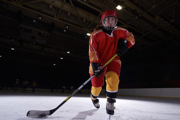 Adolescente enfants joueur de hockey sur glace en action des coups de rondelle avec stick