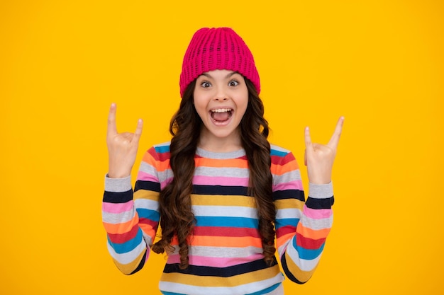 Adolescente étonnée adolescente moderne 12 13 14 ans portant un chandail et un bonnet tricoté sur fond jaune isolé