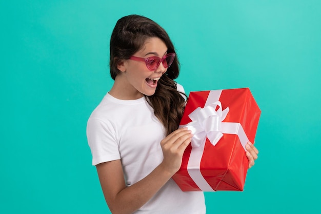 Adolescente étonnée à la mode dans une boîte-cadeau ouverte de lunettes de soleil, étonnement.