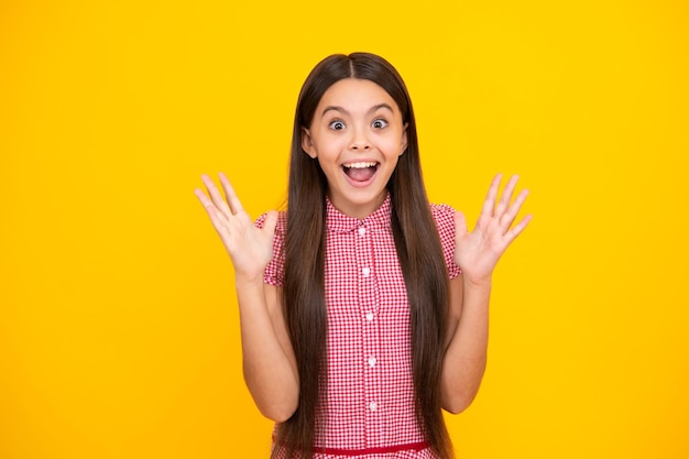 Adolescente étonnée Portrait d'une fille enfant joyeuse avec les mains levées Adolescent caucasien criant isolé sur jaune Expression excitée joyeuse et heureuse