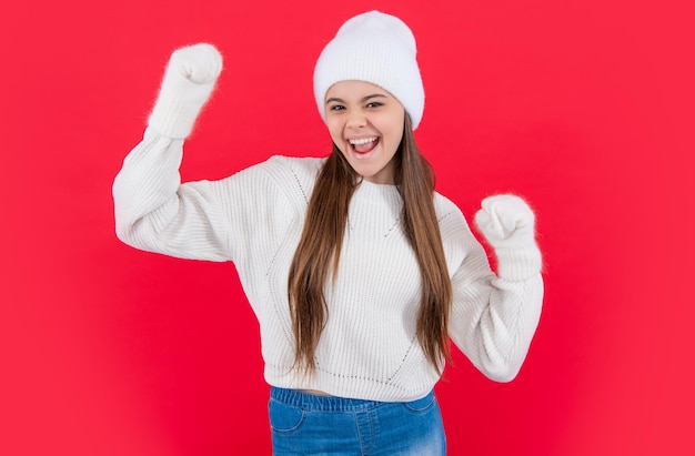 Adolescente étonnée en pull et mitaines en tricot d'hiver chaud en studio adolescente d'hiver