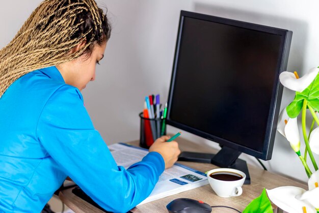 Une adolescente ou une étudiante qui utilise un ordinateur et boit du café, une fille qui travaille en ligne ou qui étudie.