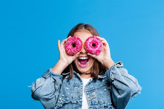 Adolescente excitée couvrant les yeux avec des beignets