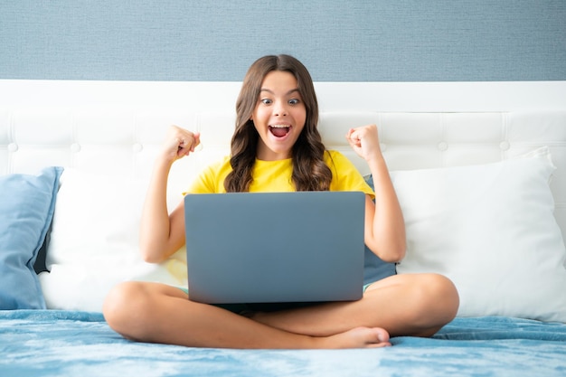 Adolescente excitée émotionnelle expressive Adolescente enfant fille travaillant sur un ordinateur portable pc couché